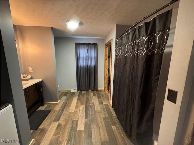 bathroom with wood-type flooring, vanity, and a textured ceiling