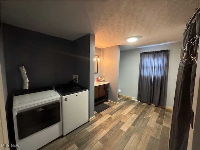 laundry room featuring light hardwood / wood-style flooring, washer and clothes dryer, and a textured ceiling