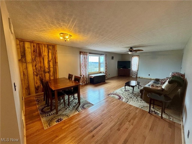 dining area with ceiling fan, wood-type flooring, and a textured ceiling