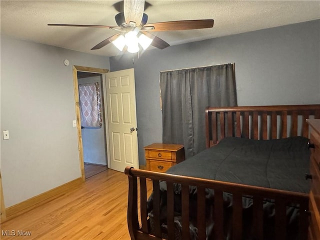 bedroom featuring ceiling fan, light hardwood / wood-style floors, and a textured ceiling