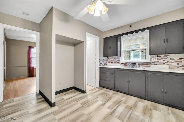 kitchen featuring ceiling fan, sink, backsplash, and light hardwood / wood-style floors