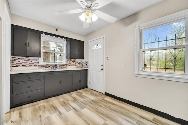 kitchen with tasteful backsplash, plenty of natural light, sink, and light wood-type flooring