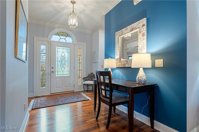 foyer featuring hardwood / wood-style flooring, crown molding, and a notable chandelier