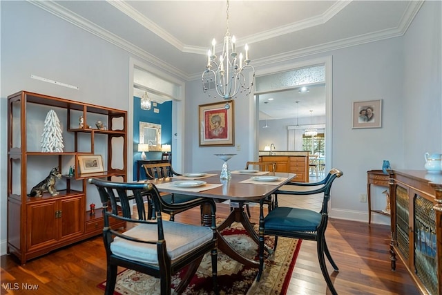 dining space with dark wood-type flooring, ornamental molding, a tray ceiling, and a notable chandelier