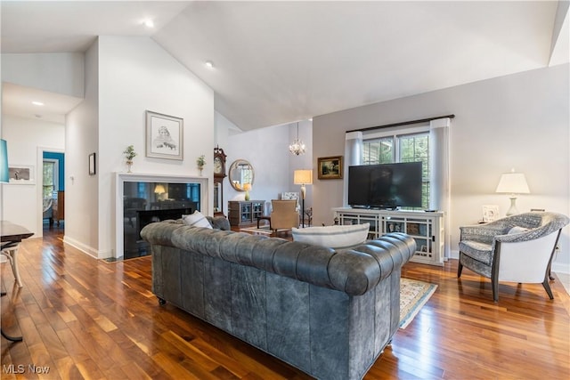 living room with dark wood-type flooring, a chandelier, high vaulted ceiling, and a tile fireplace