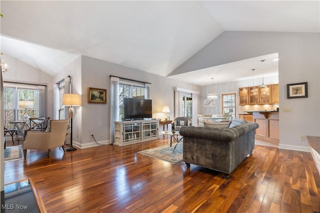 living room featuring vaulted ceiling, a notable chandelier, and dark hardwood / wood-style flooring