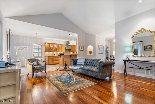 living room featuring a notable chandelier, vaulted ceiling, and light hardwood / wood-style floors