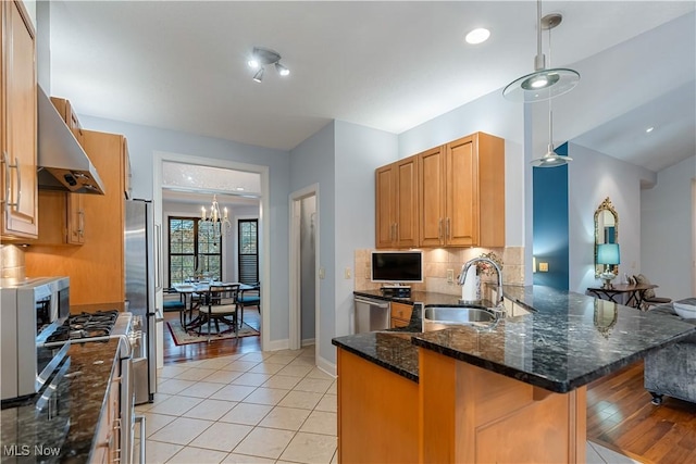 kitchen with sink, a breakfast bar area, dark stone counters, kitchen peninsula, and stainless steel appliances