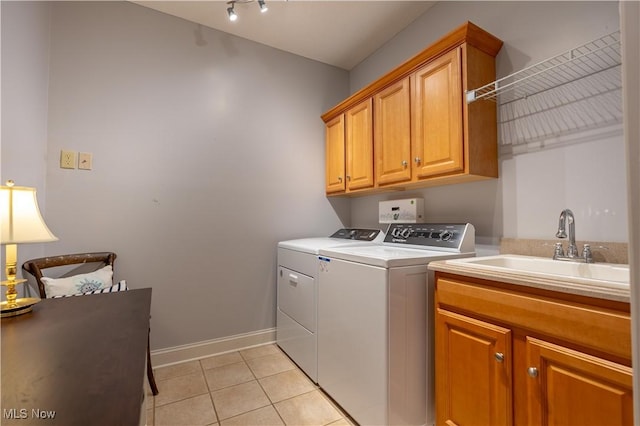 washroom with cabinets, sink, washing machine and dryer, and light tile patterned floors