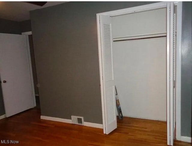 unfurnished bedroom featuring a closet, wood-type flooring, and white fridge