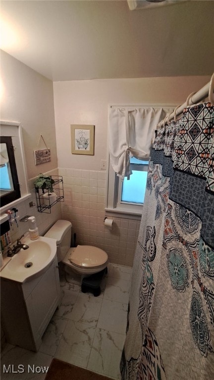 bathroom featuring tile walls, vanity, toilet, and walk in shower