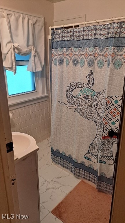 bathroom with vanity, curtained shower, and tile walls