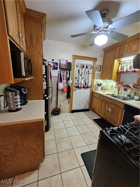 kitchen with sink, light tile patterned floors, black appliances, and ceiling fan