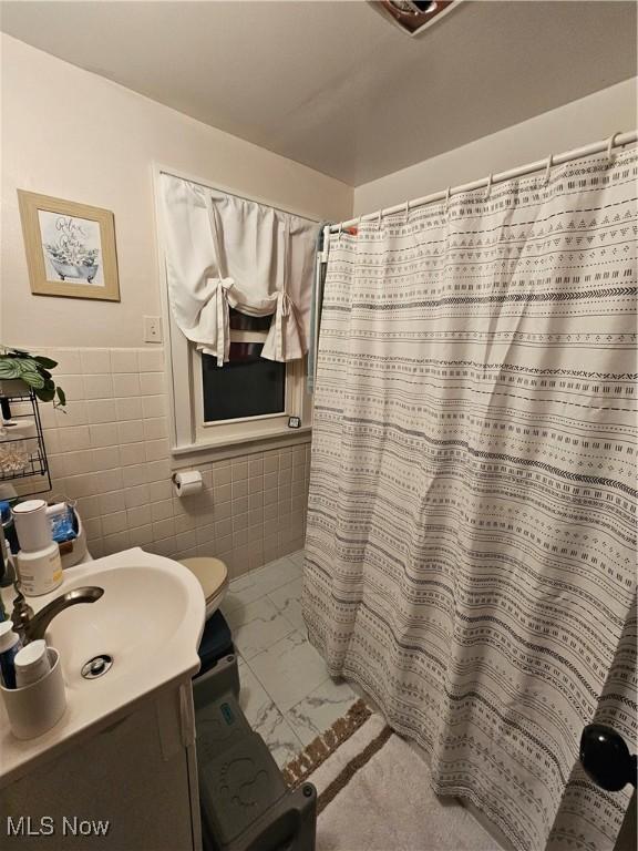 bathroom with vanity, tile walls, curtained shower, and toilet