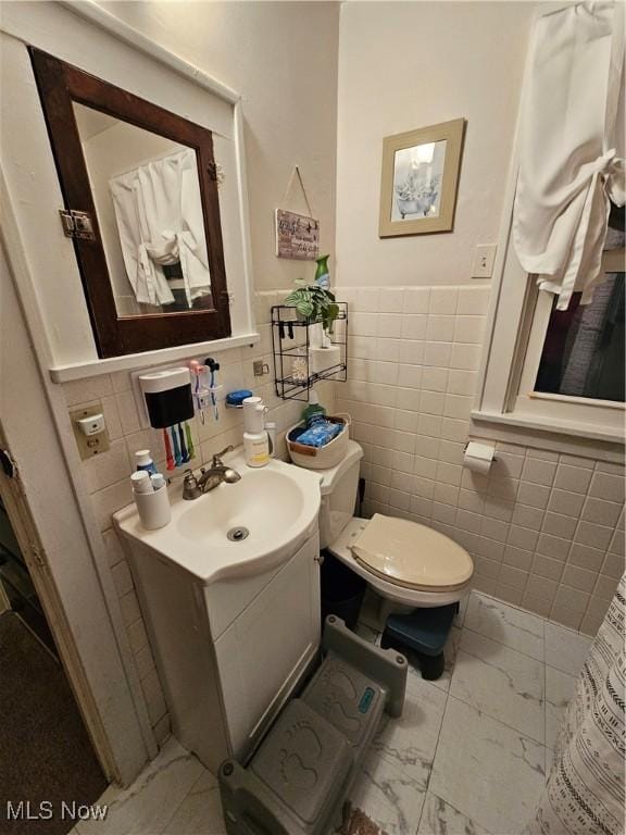 bathroom with vanity, toilet, and tile walls