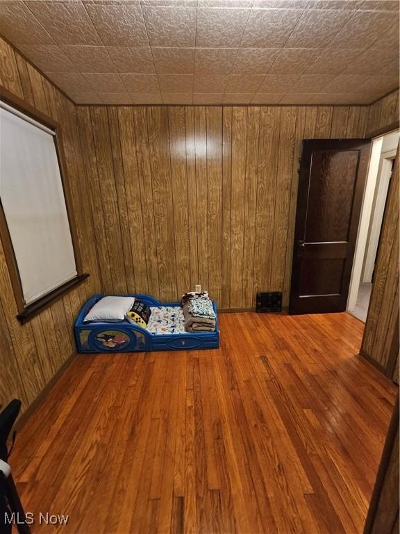 unfurnished bedroom with wood-type flooring and wooden walls