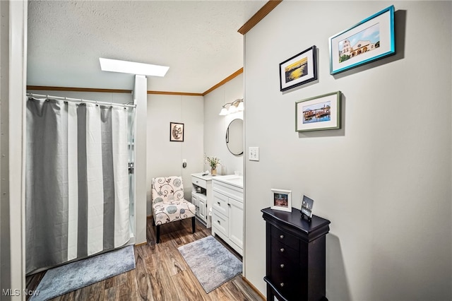 bathroom featuring crown molding, vanity, hardwood / wood-style floors, and a textured ceiling