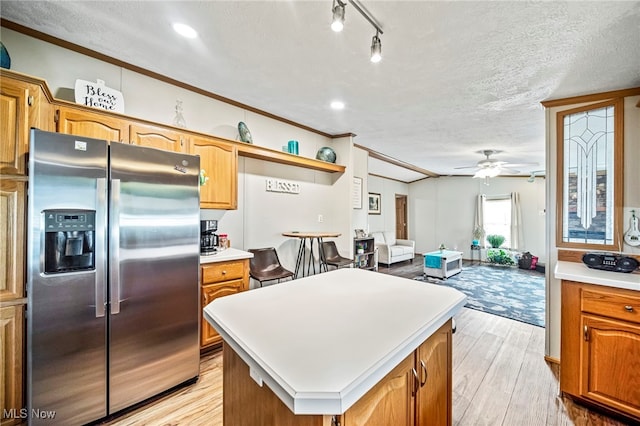 kitchen with light hardwood / wood-style floors, a center island, stainless steel fridge with ice dispenser, and a textured ceiling