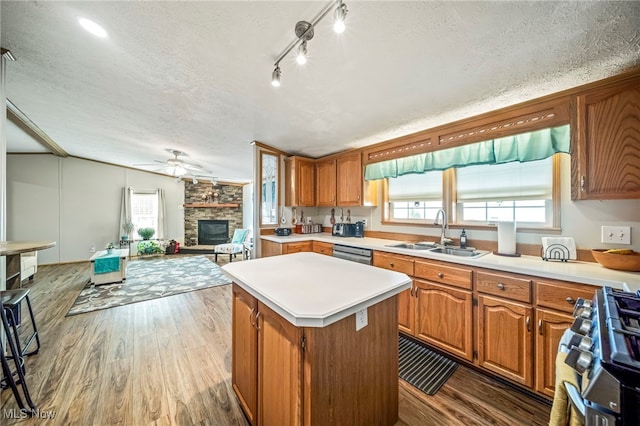 kitchen featuring sink, dark wood-type flooring, a fireplace, gas stove, and a kitchen island