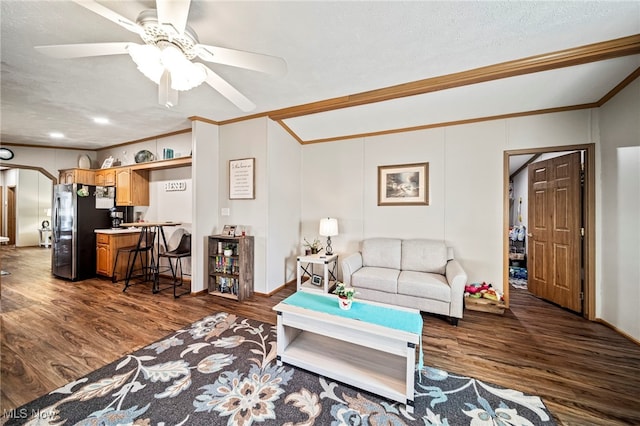 living room with dark wood-type flooring, ceiling fan, ornamental molding, and a textured ceiling