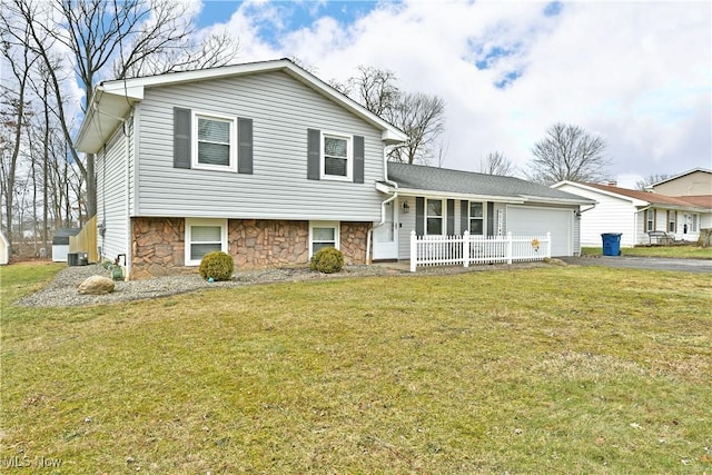 tri-level home featuring a porch, a garage, a front yard, and central AC unit