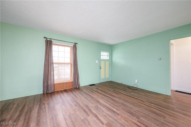 empty room with dark hardwood / wood-style flooring and a textured ceiling