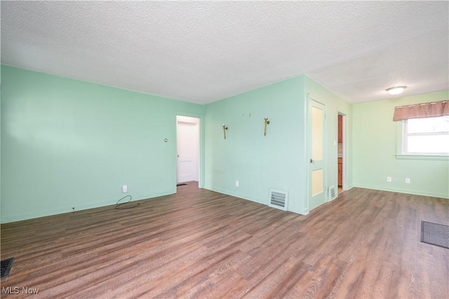 spare room featuring wood-type flooring and a textured ceiling