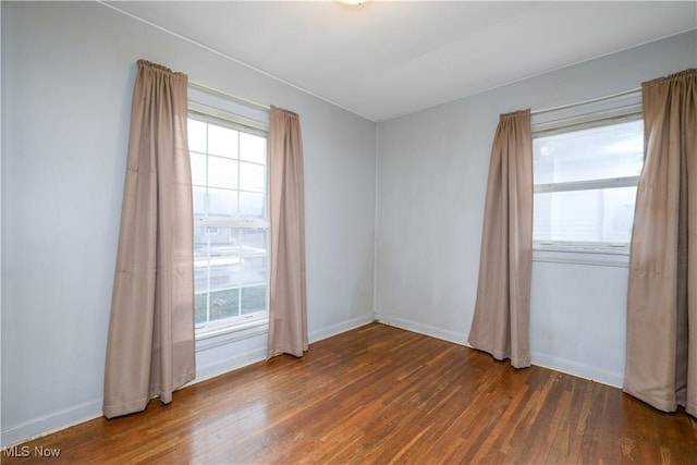 empty room featuring a healthy amount of sunlight and dark hardwood / wood-style floors