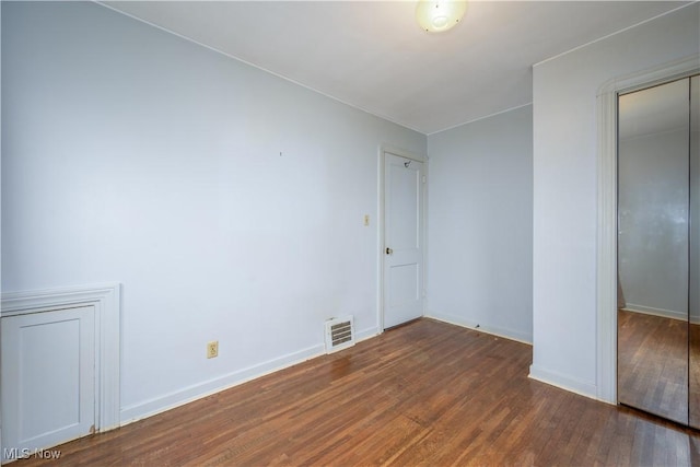 unfurnished bedroom with dark wood-type flooring and a closet