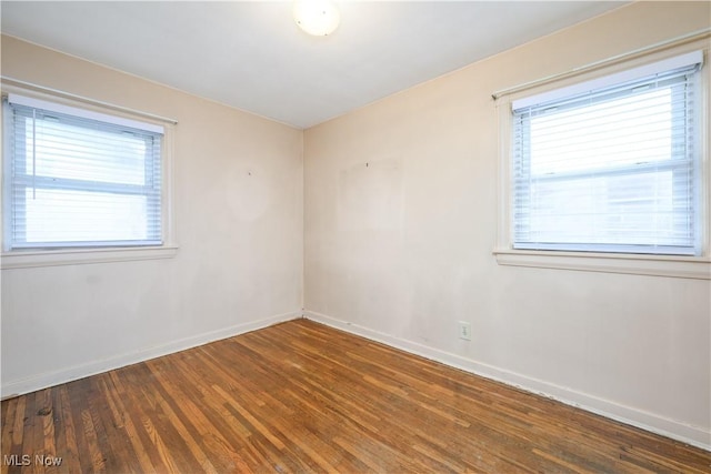 empty room with dark wood-type flooring and a wealth of natural light