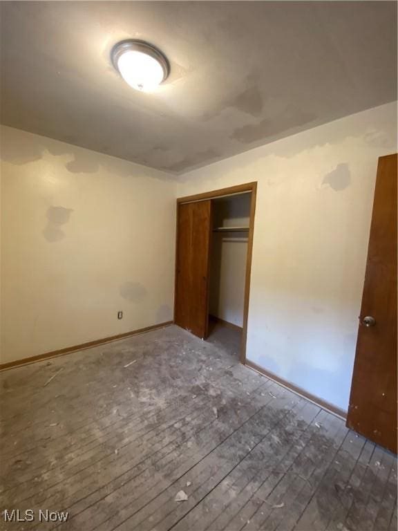 unfurnished bedroom featuring dark wood-type flooring and a closet