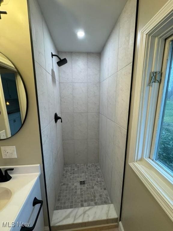 bathroom with tiled shower and vanity