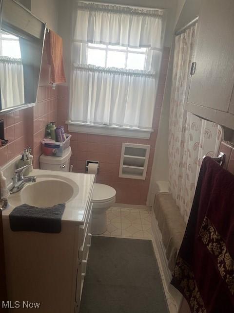 full bathroom featuring toilet, a healthy amount of sunlight, shower / bathtub combination with curtain, and vanity