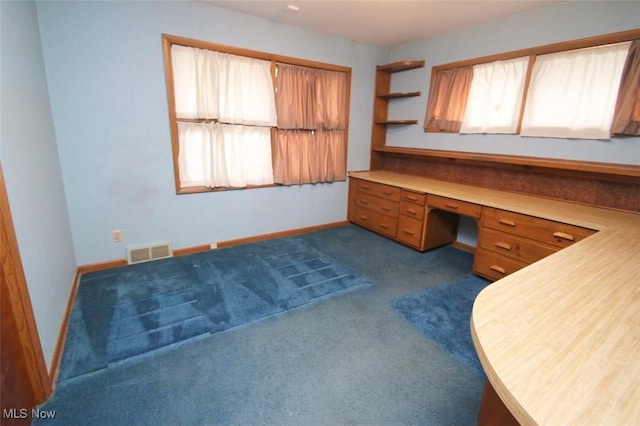 carpeted office with a healthy amount of sunlight and built in desk