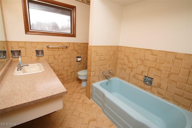 bathroom featuring a tub to relax in, toilet, tile walls, vanity, and tile patterned flooring