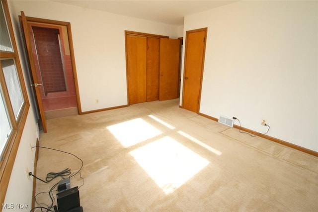 unfurnished bedroom featuring light carpet and a closet