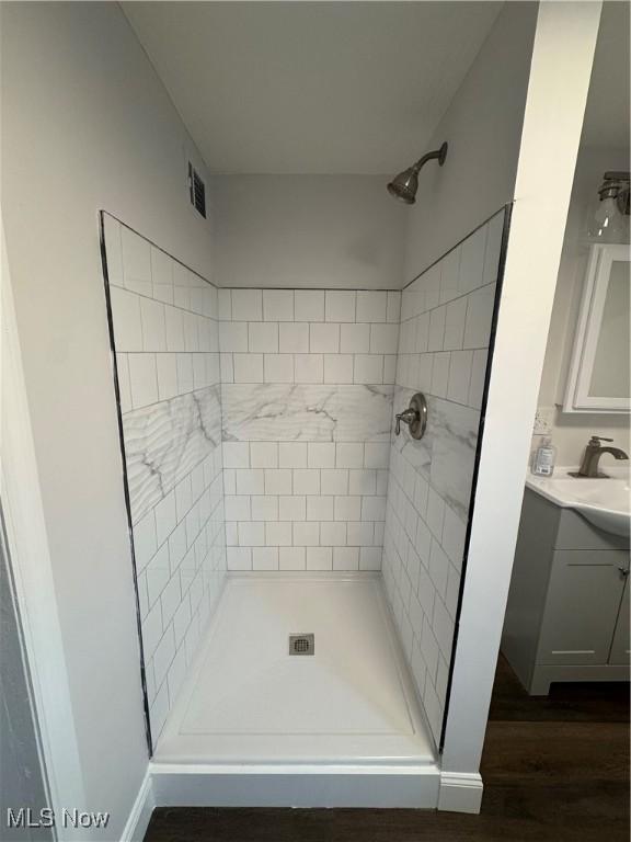 bathroom featuring vanity, wood-type flooring, and tiled shower