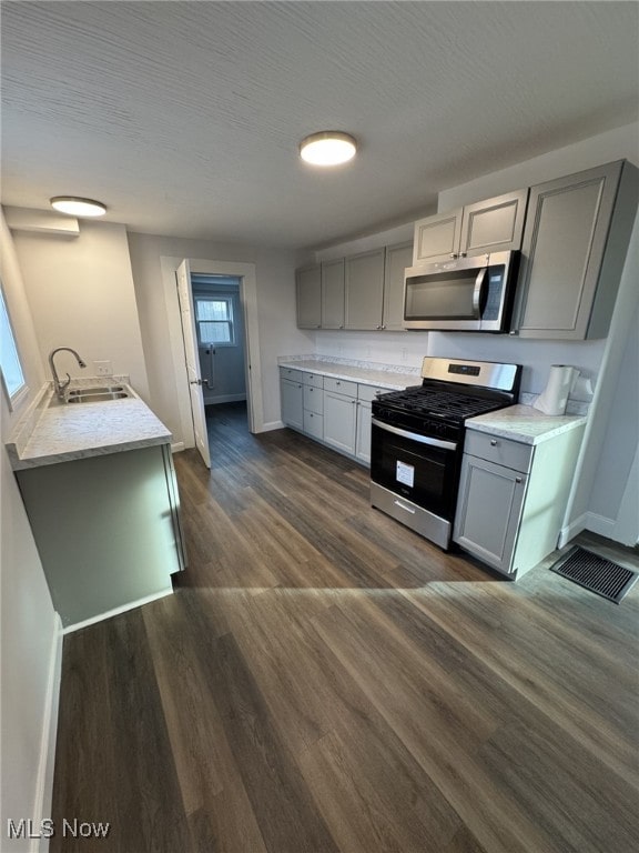 kitchen with stainless steel appliances, dark hardwood / wood-style flooring, gray cabinets, and sink