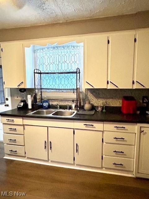 kitchen featuring white cabinetry, sink, dark wood-type flooring, and a healthy amount of sunlight