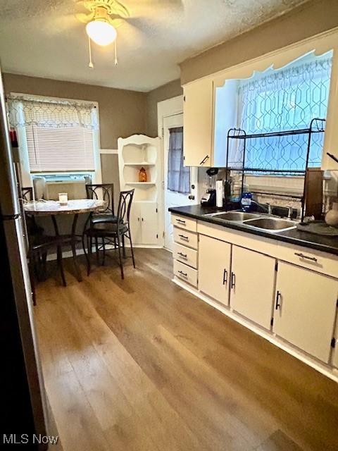 kitchen with hardwood / wood-style flooring, white cabinetry, sink, and a textured ceiling