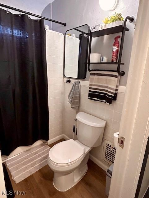 bathroom with hardwood / wood-style flooring, tile walls, curtained shower, and toilet