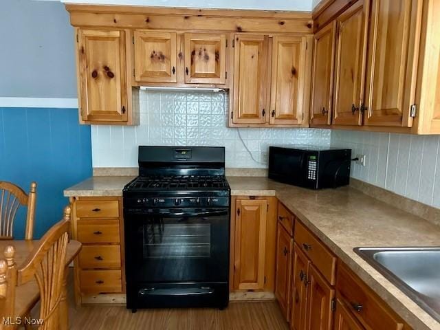 kitchen with sink, decorative backsplash, light hardwood / wood-style flooring, and black appliances