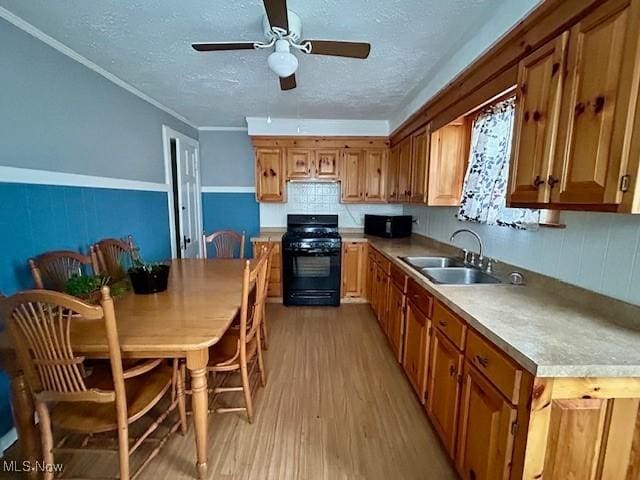 kitchen with sink, backsplash, light hardwood / wood-style floors, a textured ceiling, and black range oven