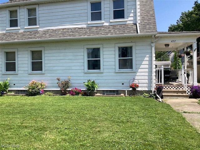 back of house with a shingled roof and a yard