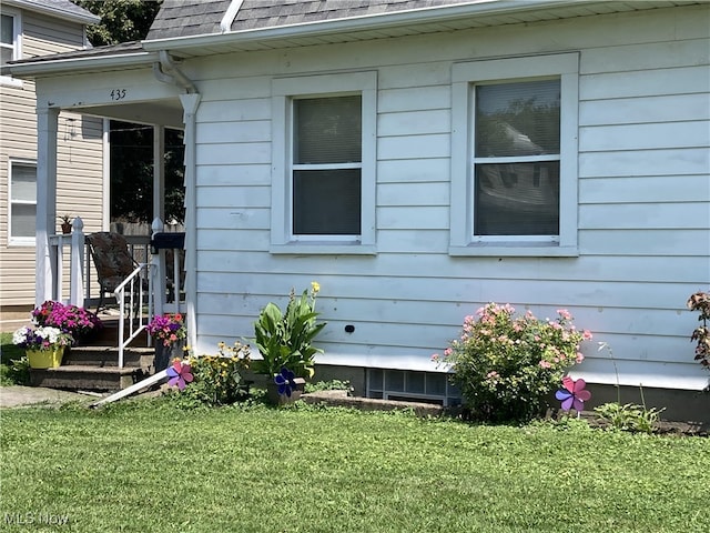 exterior space with roof with shingles and a yard