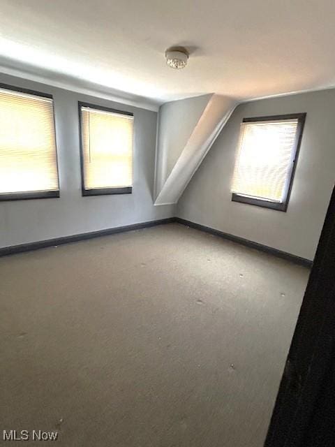 bonus room with baseboards, vaulted ceiling, and a healthy amount of sunlight