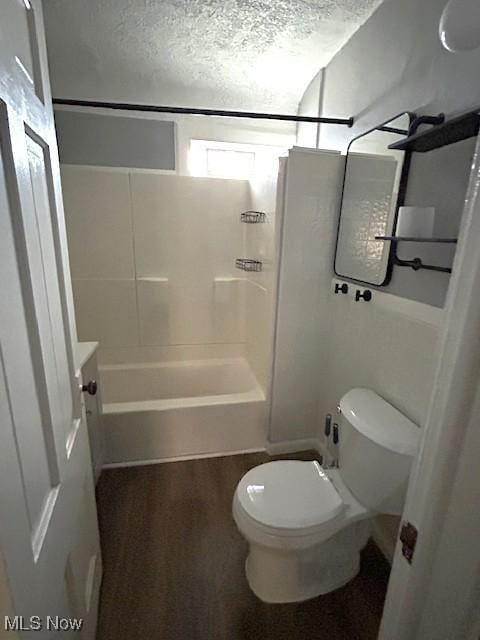 bathroom featuring toilet,  shower combination, and a textured ceiling