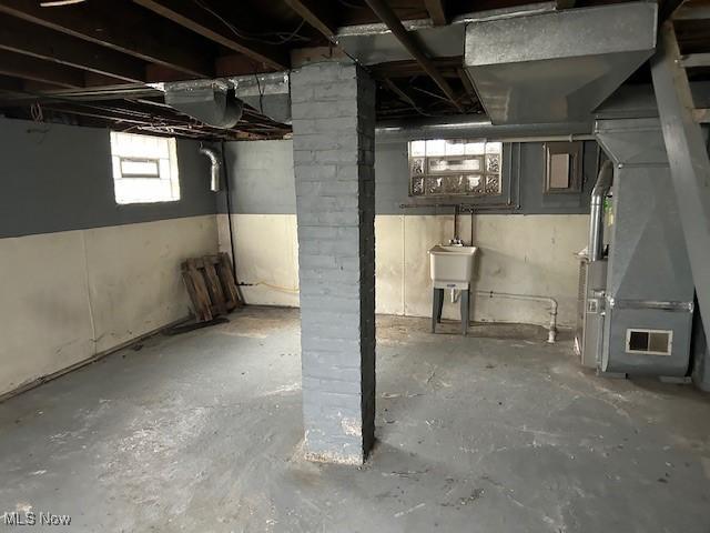 basement with a sink, visible vents, and heating unit