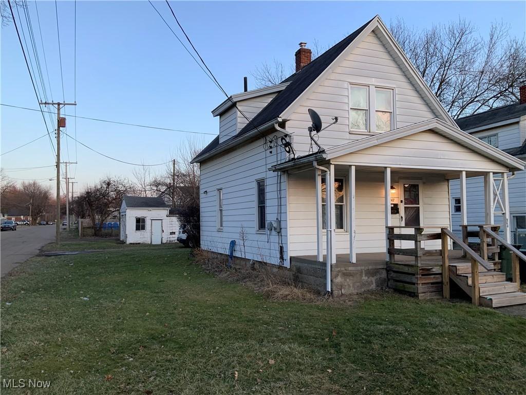 bungalow featuring a front yard, covered porch, and a shed