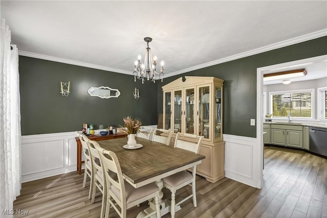 dining room featuring ornamental molding, sink, light hardwood / wood-style flooring, and a notable chandelier